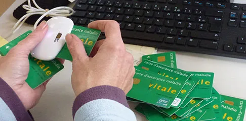 Une personne passe une carte vitale dans un lecteur.
